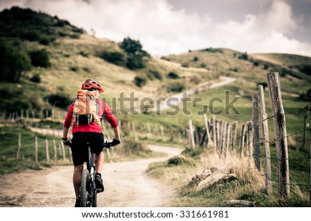 Mountain biker riding on bike singletrack trail in autumn mountains. Man rider cycling MTB on country road or single track. Sport fitness motivation, inspiration in beautiful inspirational landscape.