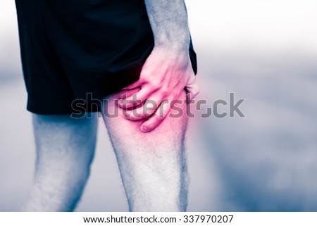 Runners leg pain on workout. Man holding sore and painful leg muscle, sprain or cramp ache filled with red pink bright place. Over trained injured person when exercising or running outdoors.