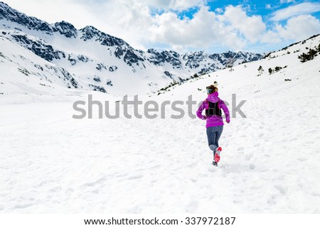 Trail running woman runner in white winter mountains on snow. Motivation and inspiration fitness concept with beautiful inspirational landscape. Active accomplish runner training outdoors in nature.