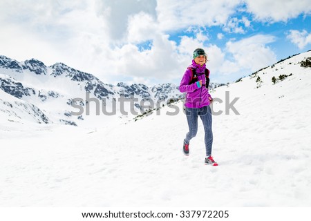 Trail running woman runner in white winter mountains on snow. Motivation and inspiration fitness concept with beautiful inspirational landscape. Active accomplish runner training outdoors in nature.