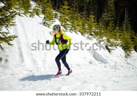 Trail running woman runner in winter mountains on snow. Motivation and inspiration fitness concept with beautiful inspirational landscape. Active accomplish runner or hiker power walking in nature.