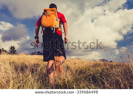 Hiking man, backpacker, climber or trail runner in mountains looking at beautiful inspirational landscape view. Fitness and healthy lifestyle outdoors in summer nature.