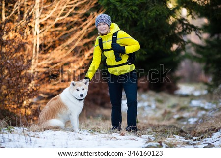 Woman hiking in white winter forest woods with akita dog. Recreation fitness and healthy lifestyle outdoors in nature. Motivation and inspirational winter landscape.