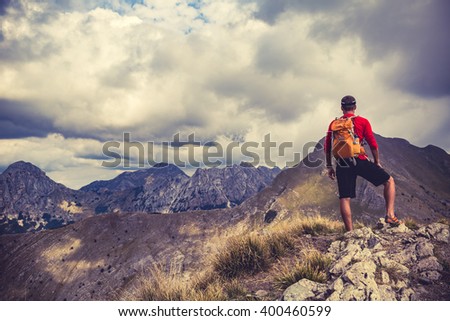 Hiking man, climber or trail runner in mountains, inspirational landscape. Motivated hiker with backpack looking at beautiful view. Travel, fitness and healthy lifestyle outdoors in summer nature.