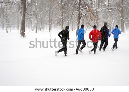 People running on snow in winter park, runners exercising outdoors, motion blur.