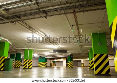 Parking lot, underground garage of shopping center. Neon light in bright industrial building.