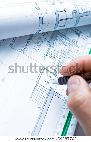 Blueprints and architect\'s hand with pencil drawing housing project.