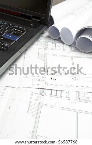 Laptop and engineer blueprints on drawing table in office