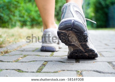 Woman walking on sidewalk, sport shoes closeup
