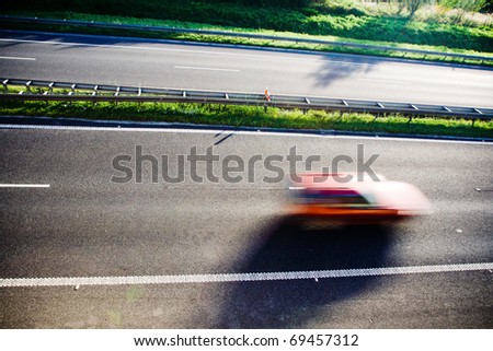 Blurred red car speeding on highway