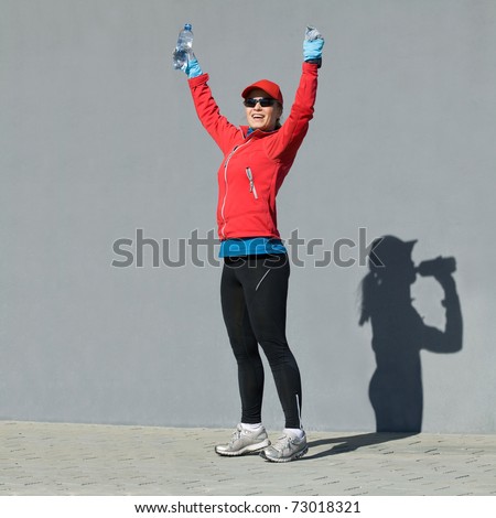 Happy Woman Shadow Runner Motivation and Inspiration success running jogging, winning and tired shadow on concrete wall drinking water, arms outstretched