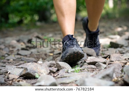 Sport shoes on trail walking running in mountains. Jogging or training outside in summer nature, motivational health and fitness concept.
