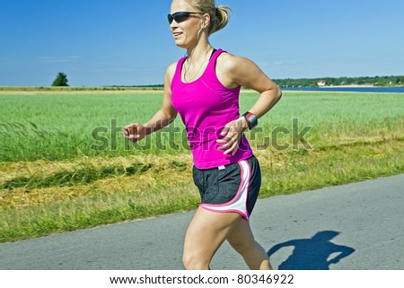 Woman running on country road, meadow and summer landscape