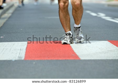 Running in marathon on city streets, sport shoes closeup