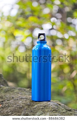 Metal water bottle in a green summer forest