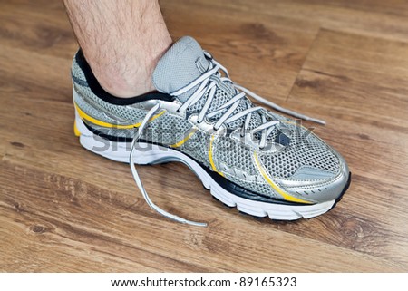 Man tying sports shoe at gym before workout, exercising indoors