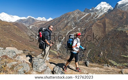 Young couple hiking in himalayas mountains in Nepal. Young people traveling in Asia, trekkers on trail in wilderness.