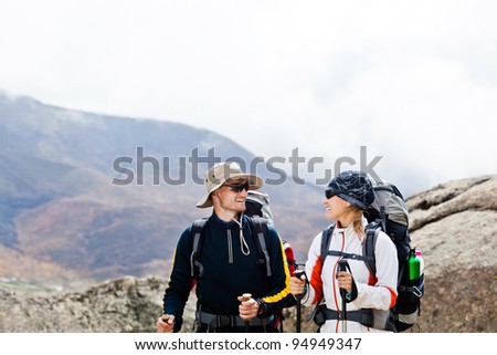 Man and woman walking in Himalaya mountains in Nepal, sport in nature. Young people traveling in Asia, trekkers on trail in wilderness.