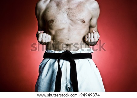 Young man training karate over red background. Fitness and sport concept at gym.