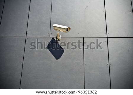 Security camera on gray modern building wall, technology in city