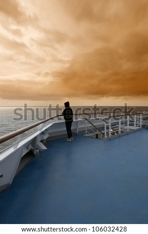 One woman is looking at the horizon enjoying the sunset from a deck of a cruise ship