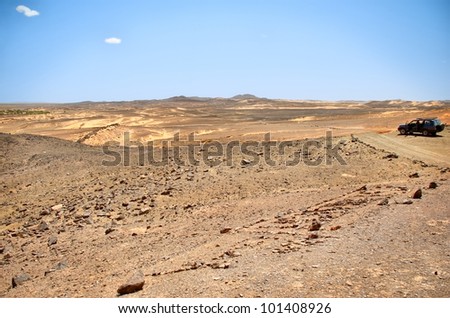 A j4x4 car on a desert path reaches the point of view on a desert panorama