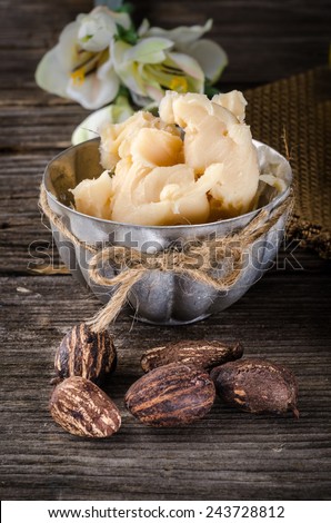 A cup full with shea butter with shea nuts on a rusty table