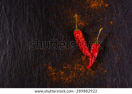 Chili peppers on black stone with chili powder