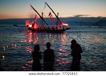 CAMOGLI, ITALY - AUGUST 1: a traditional vessel come near the beach, while people leave colored candles to the sea in Camogli, Italy, August 1, 2010. This festival take place the 1st sunday of august