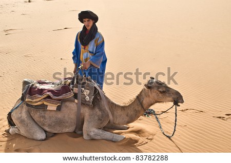 MERZOUGA, MOROCCO- AUGUST 16: Unidentified berber man wait tourist near his dromedary in Merzouga, Morocco on August 16, 2011. Many berber men work as guides for day-trips in the Sahara desert.