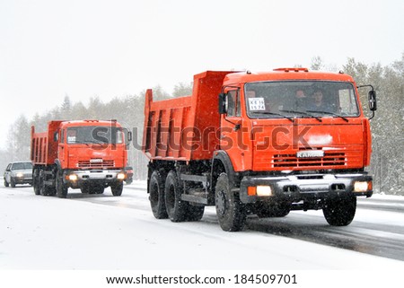 CHELYABINSK REGION, RUSSIA - SEPTEMBER 28, 2008: Orange KAMAZ 65115 dump trucks at the interurban road during an anomalous cataclysm in the form of heavy snowfall at the Ural mountains.