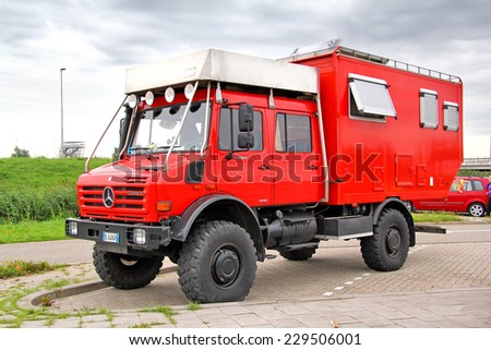 NORTH BRABANT, NETHERLANDS - AUGUST 10, 2014: Red off-road motorhome truck Unimog U4000 at the interurban road.
