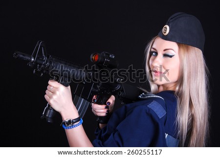 Woman in the marine uniform with an assault rifle over black background
