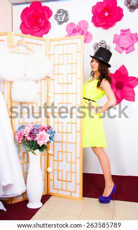 Happy young woman in a top hat behind the screen