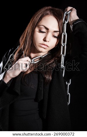 Beautiful young woman with chains over black background