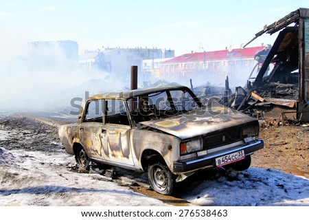 NOVYY URENGOY, RUSSIA - MAY 10, 2015: Old car near the wooden residential house after a heavy fire.