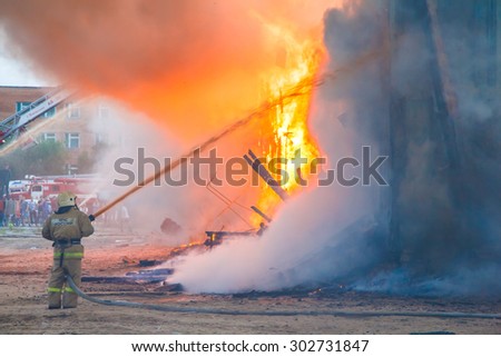 Fireman extinguishes a burning old wooden residential house