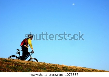 Man riding his bike alone and white moon on the sky