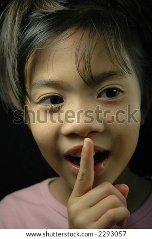 Little girl covering her mouth with one finger