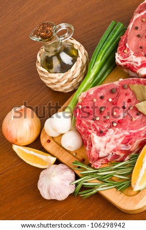 raw fresh meat with rosemary, onion, garlic, peppercorn, lemon and oil