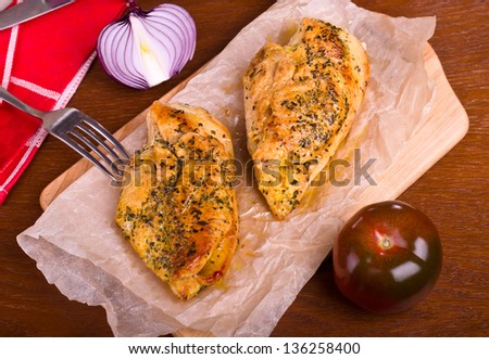 Fried chicken fillets on a wooden board and vegetables in the table