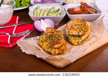 Fried chicken fillets on a wooden board and vegetables in the table