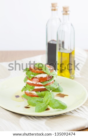 Slices of tomatoes and mozzarella with basil leaves, olive oil and balsamic vinegar