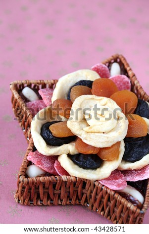 Variety of dried fruits arranged in flower shape in a star shaped wicker basket on a Christmas background. Shallow dof, copy space