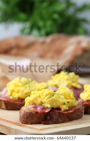 Sandwiches with scrambled eggs and bacon, garnished with chives. Shallow dof