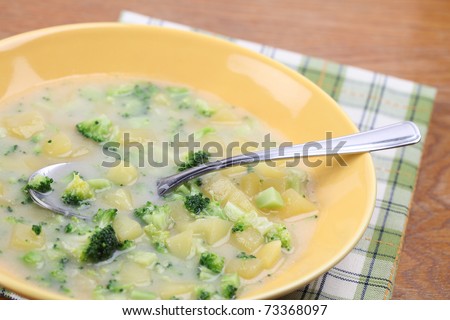 Healthy broccoli soup with potatoes on yellow plate