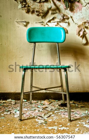 Image of a teal blue chair in an abandoned building with cracked and peeling paint illuminated by natural daylight with hard shadow.