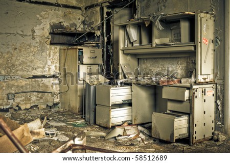 Image of a destroyed office in a derelict abandoned police station surrounded by crumbling walls with peeling paint.