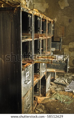 Image of an old rusty filing cabinet in a derelict abandoned police station covered in debris.