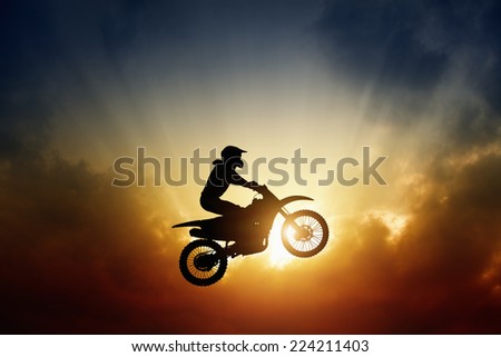 Extreme sports background - silhouette of biker jumping on motorbike on sunset